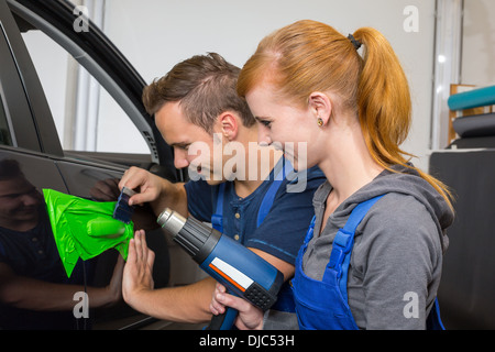 car wrapping professional wrapping car door handle in colorful foil or film using a squeegee Stock Photo