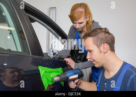 Car wrapping specialist wraps a car door handle with adhesive foil or film Stock Photo