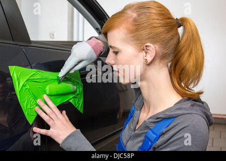 car wrapping professional wrapping car door handle in colorful foil or film using a squeegee Stock Photo