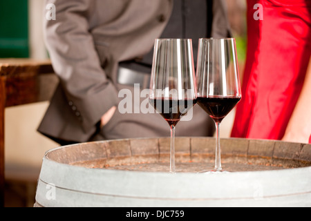 Two glass of red wine with couple standing in background Stock Photo
