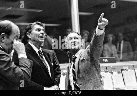 US President Ronald Reagan is briefed by NASA JSC Director Christopher C. Kraft Jr., who points toward the orbiter spotter on the projection plotter in the front of the mission operations control room in the Johnson Space Center's Mission Control Center November 13, 1986 in Houston, TX. This picture was taken just prior to a space-to-ground conversation between STS-2 crew members Joe H. Engle and Richard H. Truly, who were orbiting Earth in the space shuttle Columbia. Stock Photo