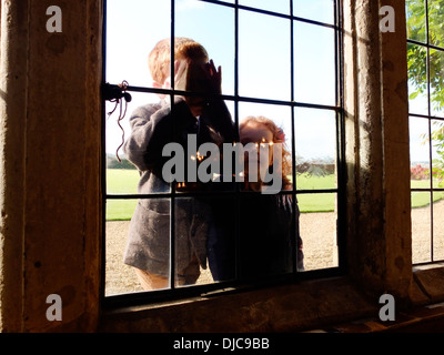 Children looking through a window Stock Photo