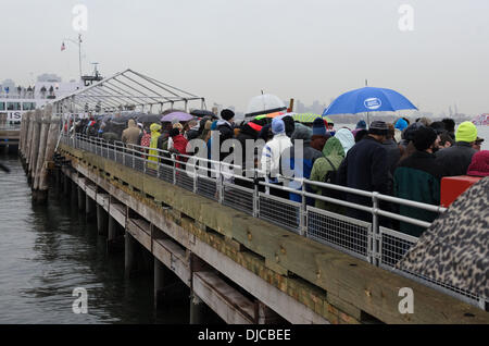 New York, NY, USA, November 26, 2013. Tourists visiting the Statue of Liberty wait for the Statue Cruises boat in a downpour. A winter storm sweeping up the East Coast of the US threatens travel plans for Thanksgiving. Credit:  Jennifer Booher/Alamy Live News Stock Photo