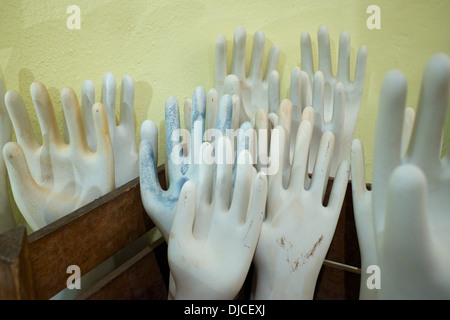Model hands reaching up from a box against a wall Stock Photo