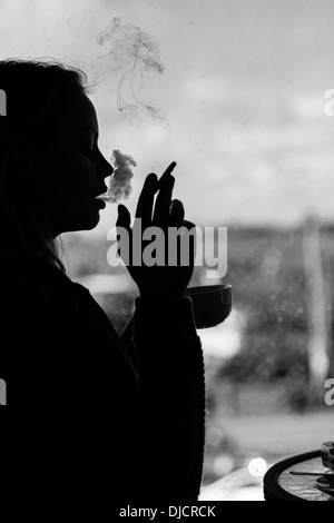 Silhouette of an attractive woman smoking cigarette Stock Photo
