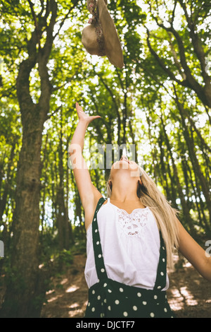 Happy gorgeous blonde throwing straw hat in the air Stock Photo