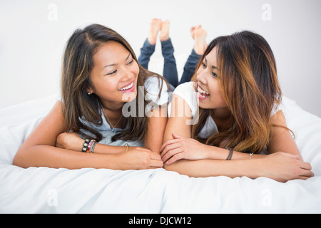 Pretty brunette sisters lying on a bed Stock Photo