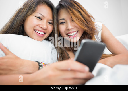 Two casual sisters using a smartphone Stock Photo