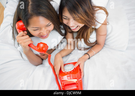 Two sisters making a call on an old fashioned dial phone Stock Photo