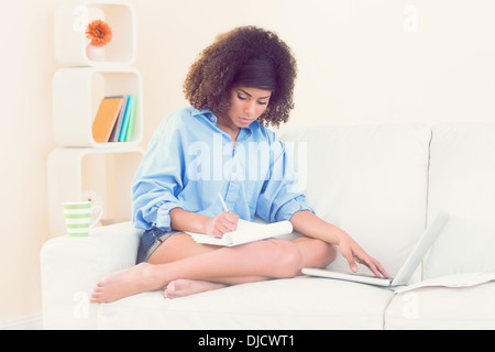 Pretty focused student taking notes using laptop Stock Photo