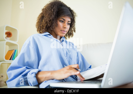 Pretty content student making notes and using laptop Stock Photo