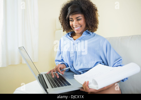 Pretty cheerful student taking notes and using laptop Stock Photo