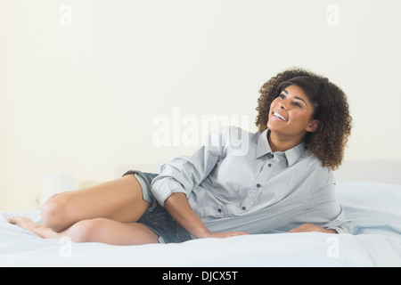 Pretty content brunette lying on bed Stock Photo