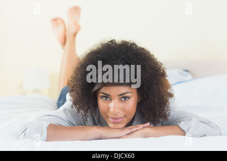 Pretty content brunette lying on bed resting head on hand Stock Photo
