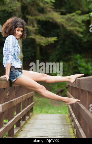 Gorgeous smiling brunette sitting on bridge Stock Photo