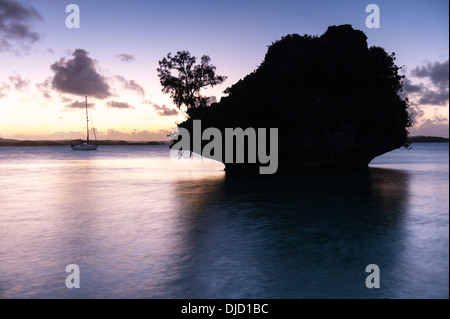 Motu - small limestone islet - at dusk with yacht at anchor, anchorage at eastern end of Fulaga lagoon, Lau Islands, Fiji. Stock Photo