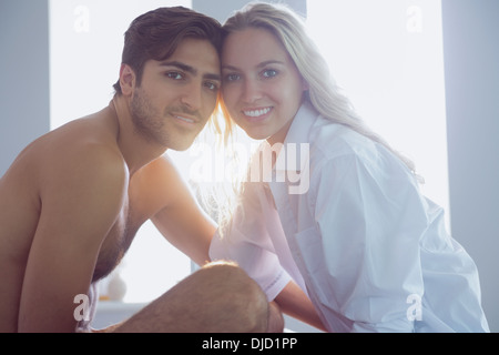 Cheerful young couple posing sitting on their bed Stock Photo