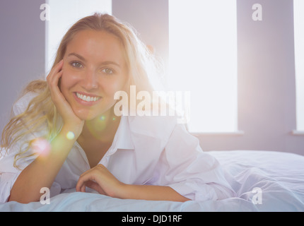 Happy young woman lying on her bed Stock Photo