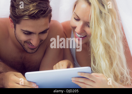 Amused young couple lying under the blanket Stock Photo