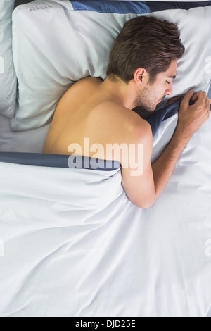 Dark haired young man sleeping in his bed Stock Photo