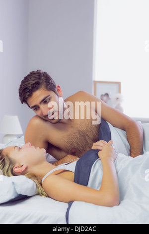 Sweet young couple talking while lying in the bed Stock Photo