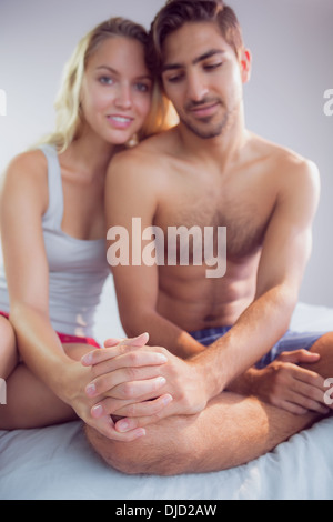 Attractive young couple sitting on bed Stock Photo