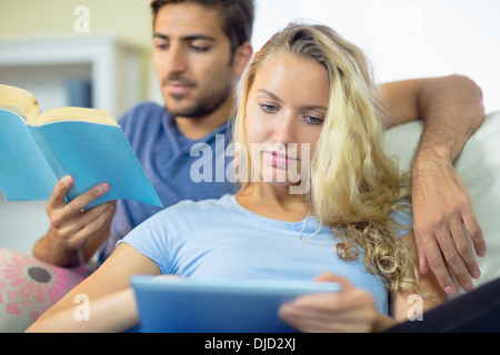 Concentrated young couple using a tablet and reading Stock Photo