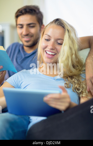 Laughing couple reading and using a tablet Stock Photo