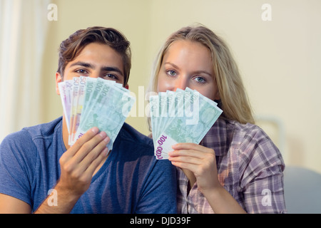 Beautiful young couple hiding their faces behind cash Stock Photo