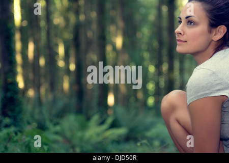 Attractive brunette woman sitting in a forest Stock Photo