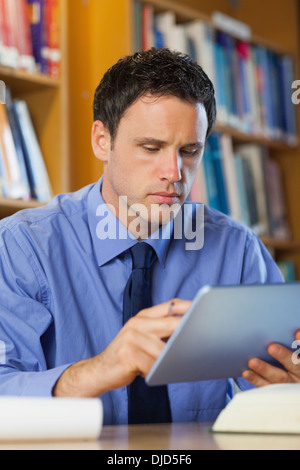 Concentrating librarian sitting at desk using tablet Stock Photo