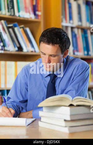 Calm librarian sitting at desk taking notes Stock Photo
