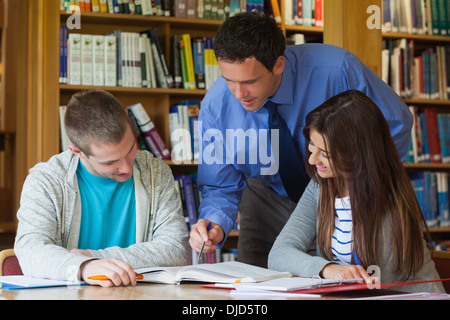 Lecturer explaining something to students and pointing at book Stock Photo