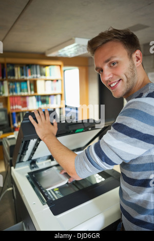 Smiling handsome student using photocopier Stock Photo