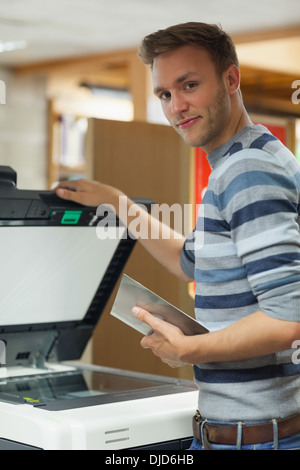 Happy handsome student using photocopier Stock Photo