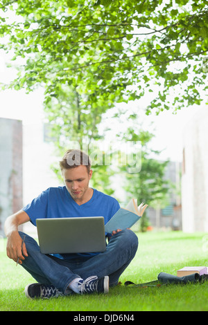 Calm handsome student sitting under tree studying Stock Photo