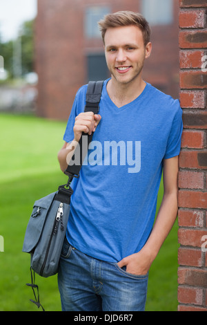 Happy handsome student leaning against wall Stock Photo