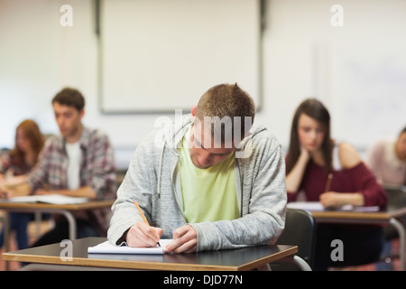 Focused young student taking notes in class Stock Photo