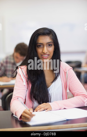 Smiling indian student listening in class looking at camera Stock Photo