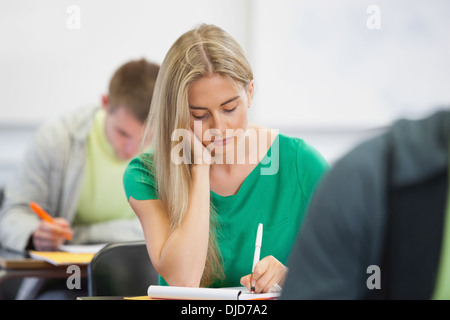 Pretty blonde student taking notes in class Stock Photo