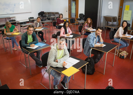 Students taking notes in class smiling up at camera Stock Photo