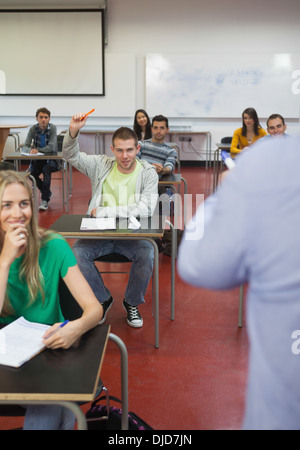 Student raising his hand to ask a question in classroom Stock Photo