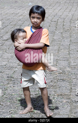 Young boy and infant brother in arms, begging on the streets of Phnom Penh Cambodia S. E. Asia Stock Photo