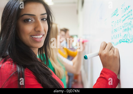 Student writing on the whiteboard in class smiling at camera Stock Photo