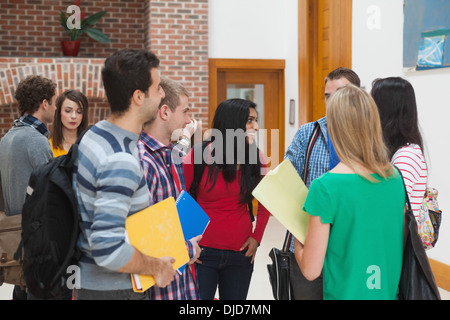 Happy students chatting together in a hallway Stock Photo