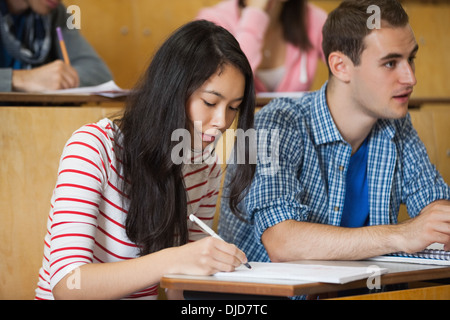 Focused students taking notes in lecture hall Stock Photo