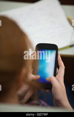Student sitting in a lecture using her smartphone Stock Photo