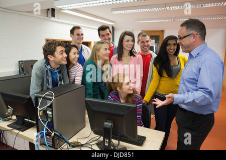 Students standing at computer chatting with their lecturer in the computer room Stock Photo