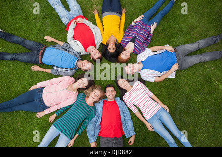 Group of students smiling at camera lying in circle on the grass on campus Stock Photo