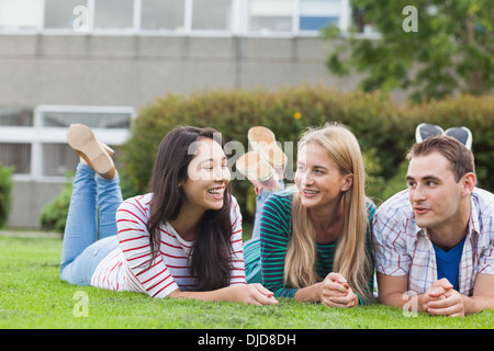 Happy young students lying on the grass on campus Stock Photo
